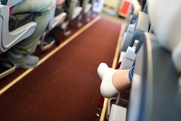 一名飞机乘客脱掉了鞋子。（Shutterstock）